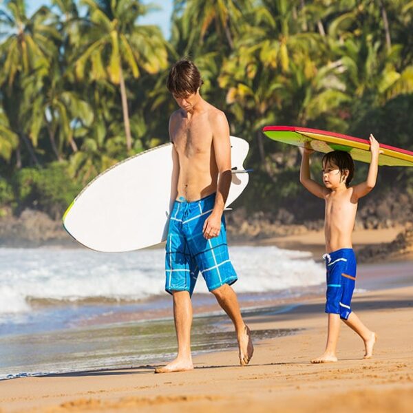 man & son on beach headed to surf-min