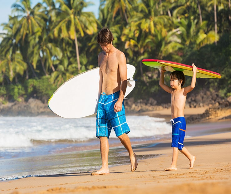 man & son on beach headed to surf-min